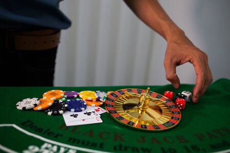 man hand hold Casino equipment placed on the green floor for risky gambling for the people who want to get rich.の写真素材