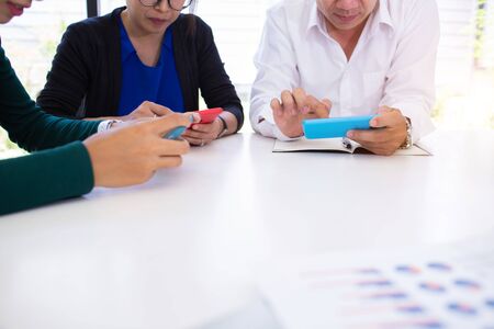 business team hands searching for data on mobile phone  with analyzing charts at his workplace.の写真素材