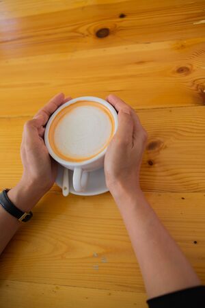Hand Women put a Latte arts coffe hot coffee on wooden table.barista love art concept.の写真素材