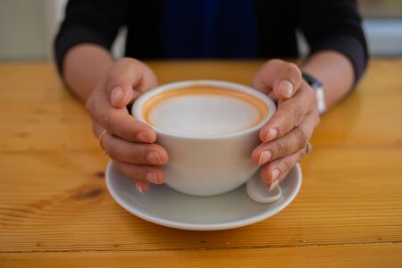 Hand Women put a Latte arts coffe hot coffee on wooden table.barista love art concept.の写真素材