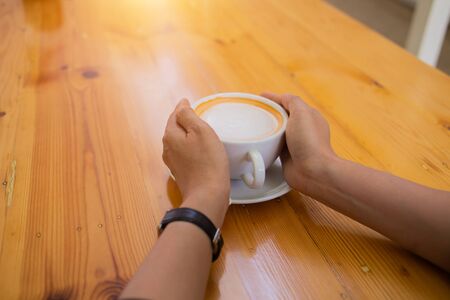 Hand Women put a Latte arts coffe hot coffee on wooden table.barista love art concept.の写真素材