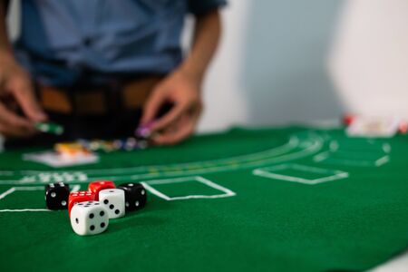 man hand hold Casino equipment placed on the green floor for risky gambling for the people who want to get rich.の写真素材