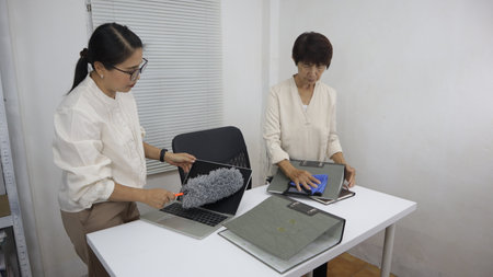 Two women are cleaning an office together.white office environment, showing teamwork and attention...