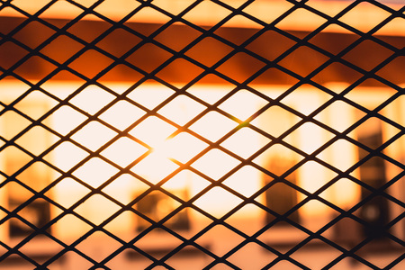 Silhouette of metal grille and light of sunsetの写真素材