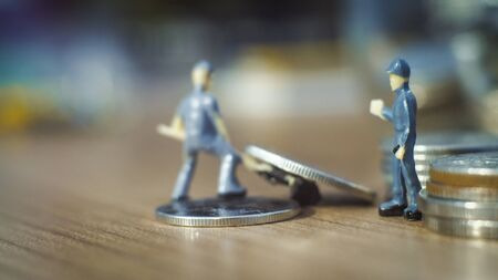 Miniature people standing on coins.and work on coins