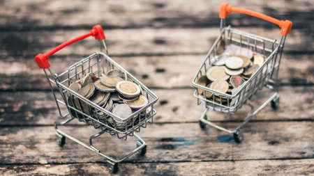 Close up coins and receipts paper on mini shopping cart with natural light background (Business and finance concept)の写真素材