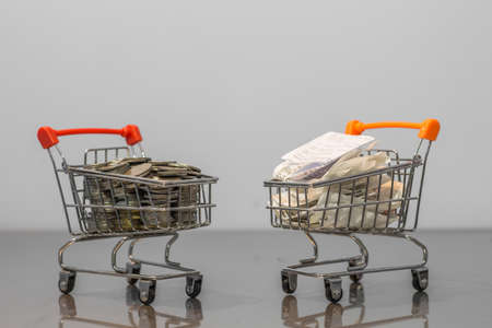 Close up coins and receipts paper on mini shopping cart with natural light background (Business and finance concept)の写真素材