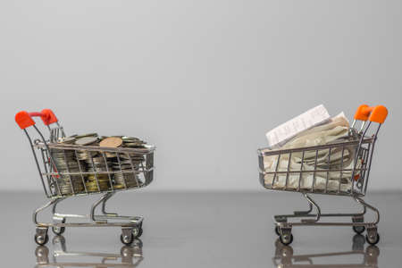 Close up coins and receipts paper on mini shopping cart with natural light background (Business and finance concept)の写真素材