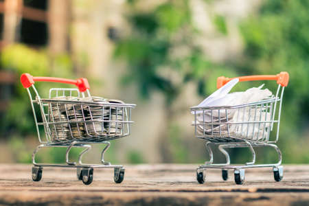 Close up coins and receipts paper on mini shopping cart with natural light background (Business and finance concept)の写真素材