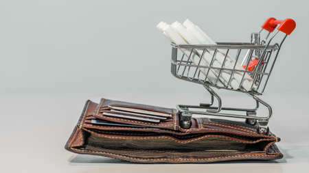 Close up cigarette on mini shopping cart on white background  with copy specs
