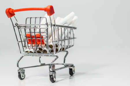 Close up cigarette on mini shopping cart on white background  with copy specsの写真素材