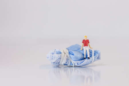 Miniature people sitting on the medical mask protection after use on white background with copy specsの写真素材