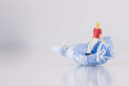 Miniature people sitting on the medical mask protection after use on white background with copy specsの写真素材