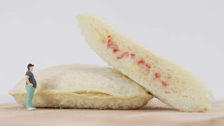 Miniature people, Fat man looks at tuna mayonnaise and crab sticks mayonnaise on white backgroundの写真素材