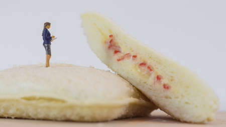 Miniature people,  Man and woman checks the quality of sandwich bread on white background (Food 
and Business Concept)の写真素材