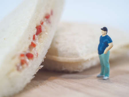 Miniature people, Fat man looks at tuna mayonnaise and crab sticks mayonnaise on white backgroundの写真素材