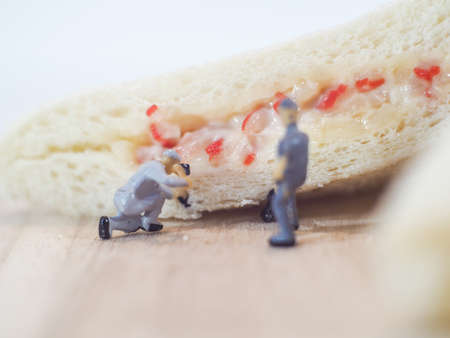 Miniature people team checks the quality of sandwich bread on white backgroundの写真素材