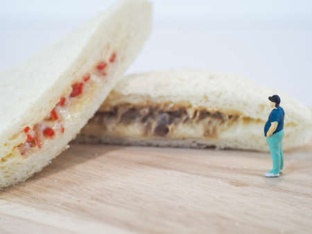 Miniature people, Fat man looks at tuna mayonnaise and crab sticks mayonnaise on white backgroundの写真素材