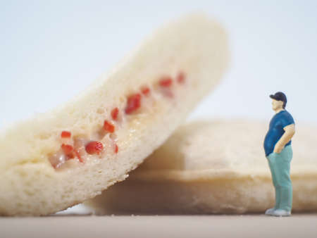 Miniature people, Fat man looks at tuna mayonnaise and crab sticks mayonnaise on white backgroundの写真素材