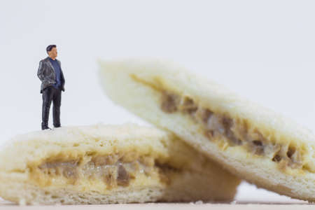 Miniature people, Business man standing on tuna mayonnaise sandwich on white background (Food 
and Business Concept)の写真素材
