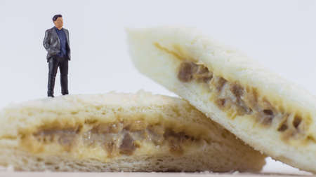Miniature people, Business man standing on tuna mayonnaise sandwich on white background (Food 
and Business Concept)の写真素材