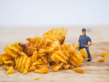 Miniature people, Workers work on  production potato chips on white background (food concept)の写真素材