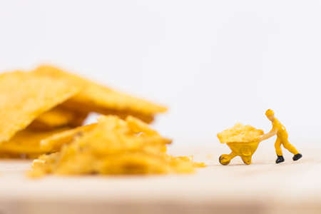 Miniature people, Workers work on  production potato chips on white background (food concept)の写真素材