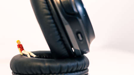 Miniature people, Young man sitting on headphone on white background (Alone music concept)の写真素材