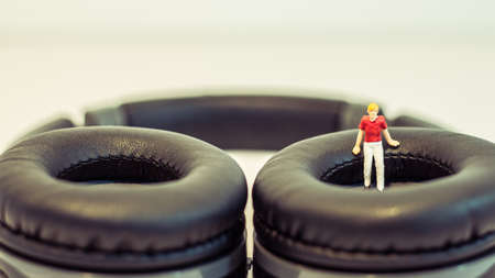 Miniature people, Young man sitting on headphone on white background (Alone music concept)の写真素材