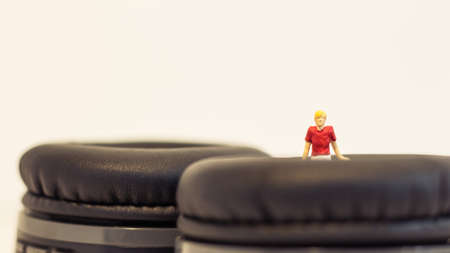 Miniature people, Young man sitting on headphone on white background (Alone music concept)の写真素材