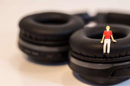 Miniature people, Young man sitting on headphone on white background (Alone music concept)の写真素材