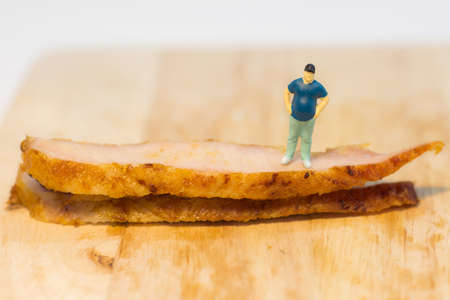 Miniature people, Fat man standing beside grilled pork neck on white background with copy spaceの写真素材