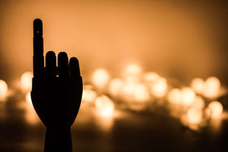 Silhouette of wooden hand with golden blurred lights backgroundの写真素材