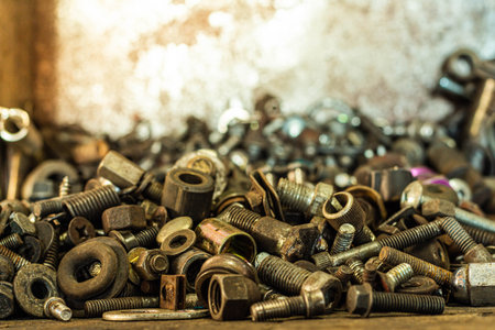 Close-up pile of old screws nuts and bolts on the old wooden tableの写真素材