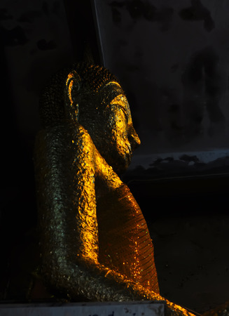 Golden Buddha statue on a dark backgroundの写真素材