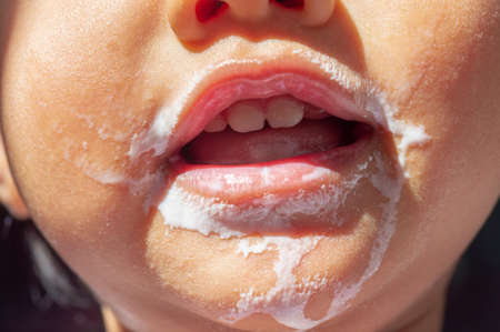selective focus of smiling kid's face is soiled from drinking milk, kid's face with soiled milkの写真素材