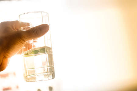 holding a glass of water at the sun on the horizon for copy space textの写真素材