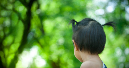 backside head of preschool girl in nature background with copy space textの写真素材