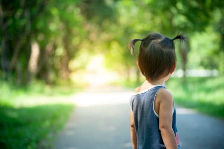 back of girl on background of road and forest park with copy space textの写真素材