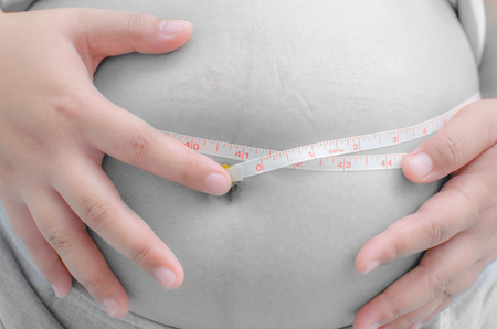 pregnant woman measuring her bellyの写真素材