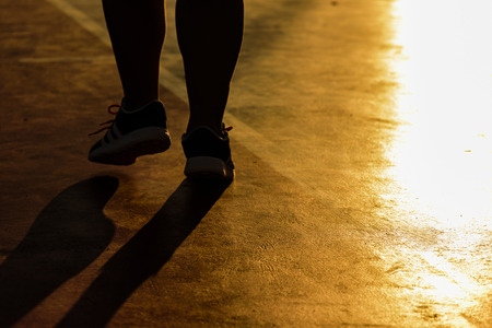 Silhouette picture, closeup shoes of woman barefoot running shoes. Female jogging on sunset background;の写真素材