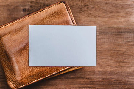 White business card on Leather purse. Mockup bank paper on wooden texture background.