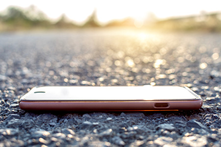 Smartphone on stone with bokeh and sunset background.の写真素材