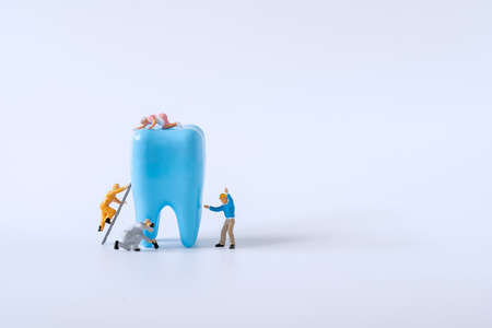 Miniature worker cleaning teeth model. dental healthcare concept.の写真素材