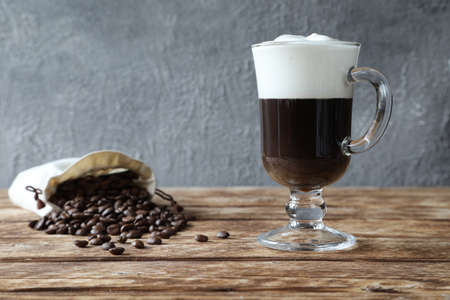 A glass of Irish coffee with coffee beans in a bagの写真素材