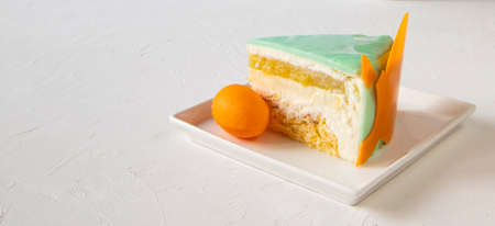 A piece of cake on a white plate with an orange on a white background