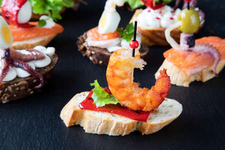 Creative Spanish sandwich that resembles a boat with a sail, consisting of cream cheese, radish, red pepper, and octopus with tentaclesの写真素材