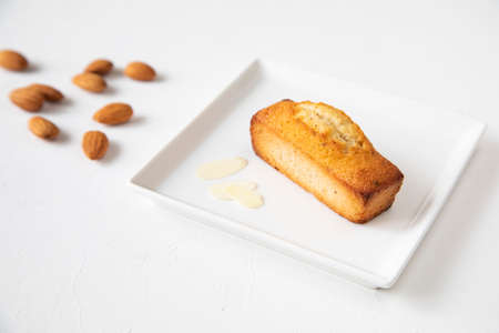 Single financier cake on a white square plate with almonds and almond shavings - a concept and the main ingredient for making French pastriesの写真素材