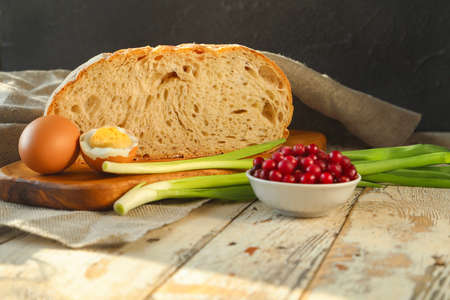 Traditional rustic breakfast - hand-made white bread with a beautiful texture with chicken eggs, red cranberries and green onions-copy spaceの写真素材