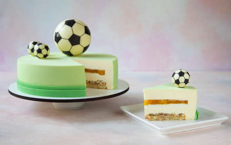 Birthday cake with chocolate football balls on top and a piece of cake with a beautiful cut lies on a square plate - close-up and copy spaceの写真素材
